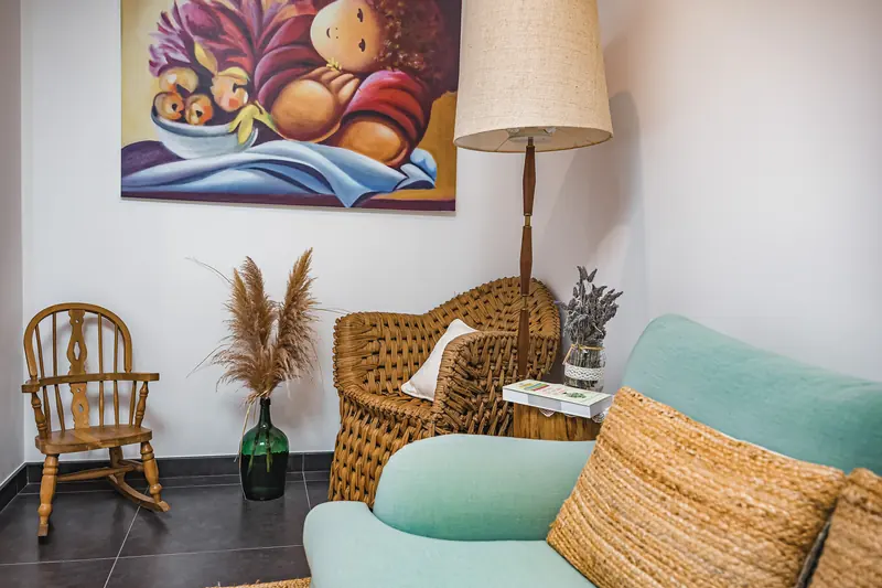 Sala de estar de um alojamento local com poltronas de vime e quadro colorido